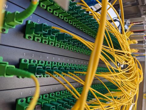 Nahaufnahme eines Patchpanels mit gelben Kabeln und grünen LC-Anschlussen